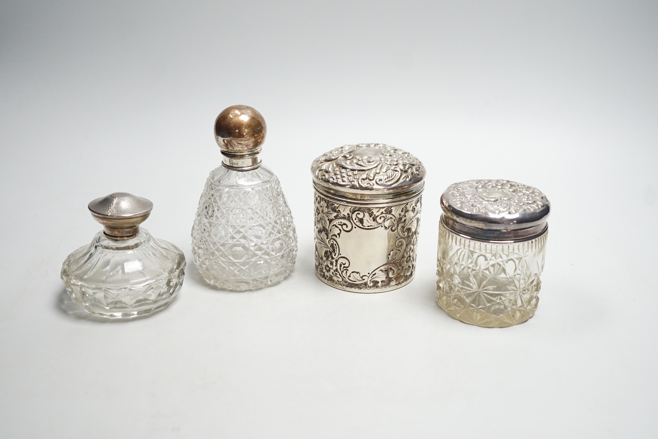 Two repousse silver lidded toilet jars, including glass, largest, 95mm and two silver mounted glass scent bottles.